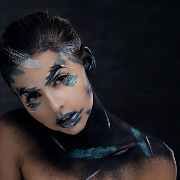 A woman with cloroful make up and painted art on a neck.